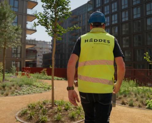 Medewerker van Heddes loopt door de groene binnentuin van MIX Amsterdam, omringd door de nieuw opgeleverde woningen